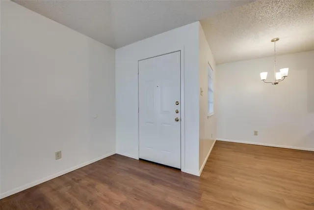 a view of an empty room with wooden floor and a ceiling fan