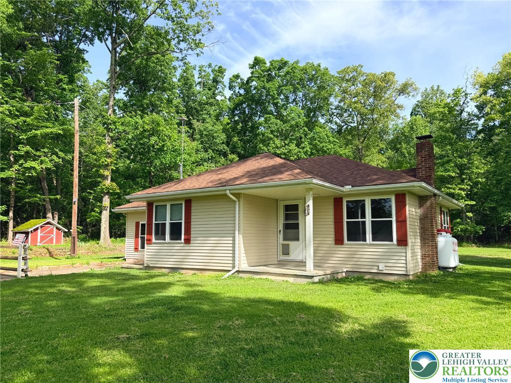 4995 Mountain Road Slatington, PA 18080 - Photo 30 of 30 A quaint residence with cheerful red shutters is nestled amongst mature trees, offering a peaceful natural setting.