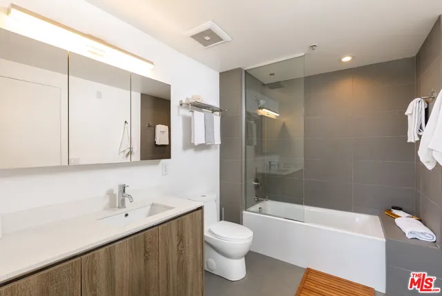 a bathroom with a bathtub shower sink mirror and toilet