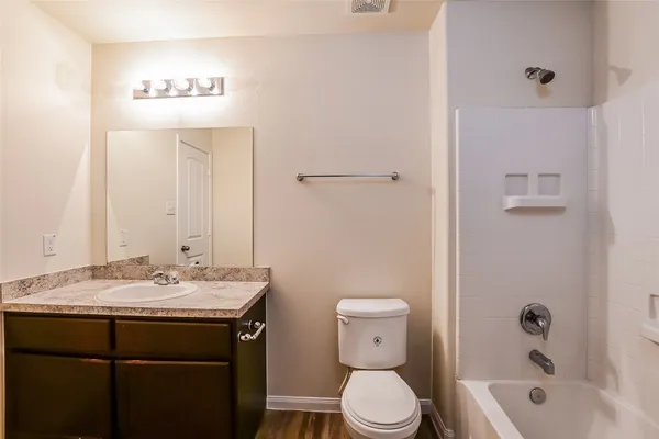 a bathroom with a granite countertop sink a toilet and shower