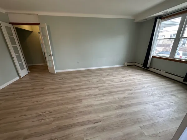 a view of an empty room with wooden floor and a window