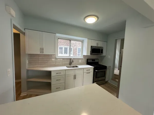 a kitchen with a sink cabinets stainless steel appliances and a window
