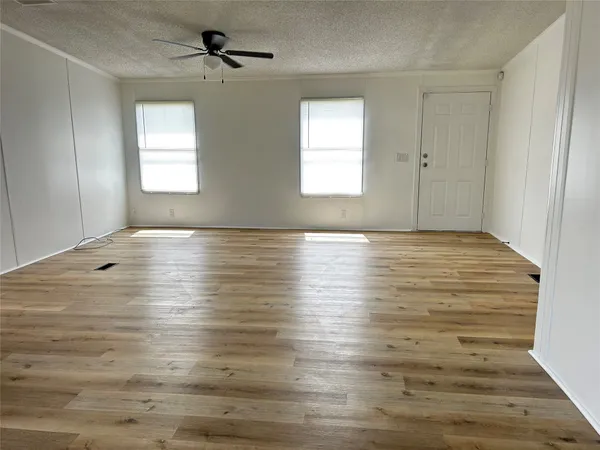 an empty room with wooden floor ceiling fan and windows