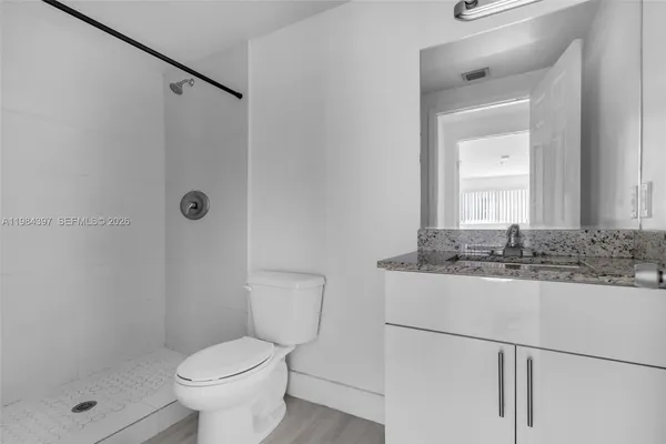 a bathroom with a granite countertop sink toilet and shower