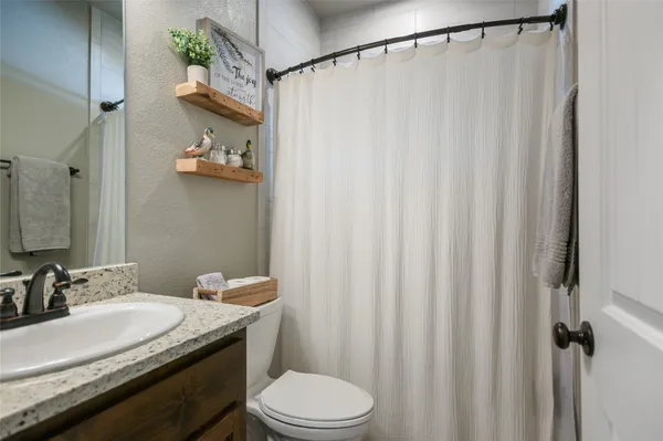 a spacious bedroom with a bed and a flat tv screen on dresser