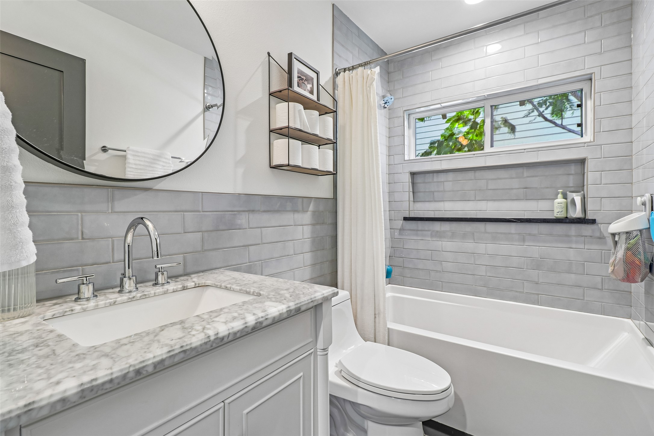1706 Perez Street, Unit 1 Austin, TX 78721 - Photo 31 of 36 A pristine bathroom features a classic subway tile surround, sleek vanity, and practical built-in shower storage.
