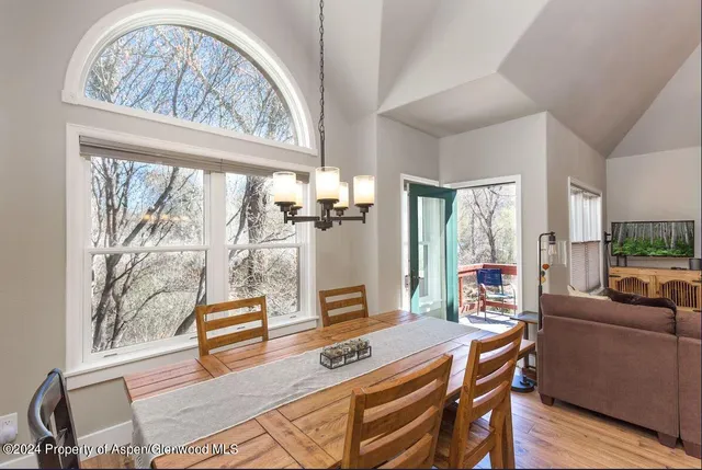 a dining room with furniture large windows and wooden floor