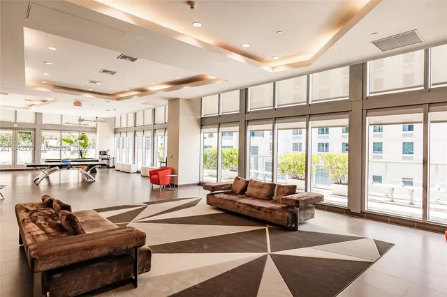 a living room with furniture a pool table and a large window