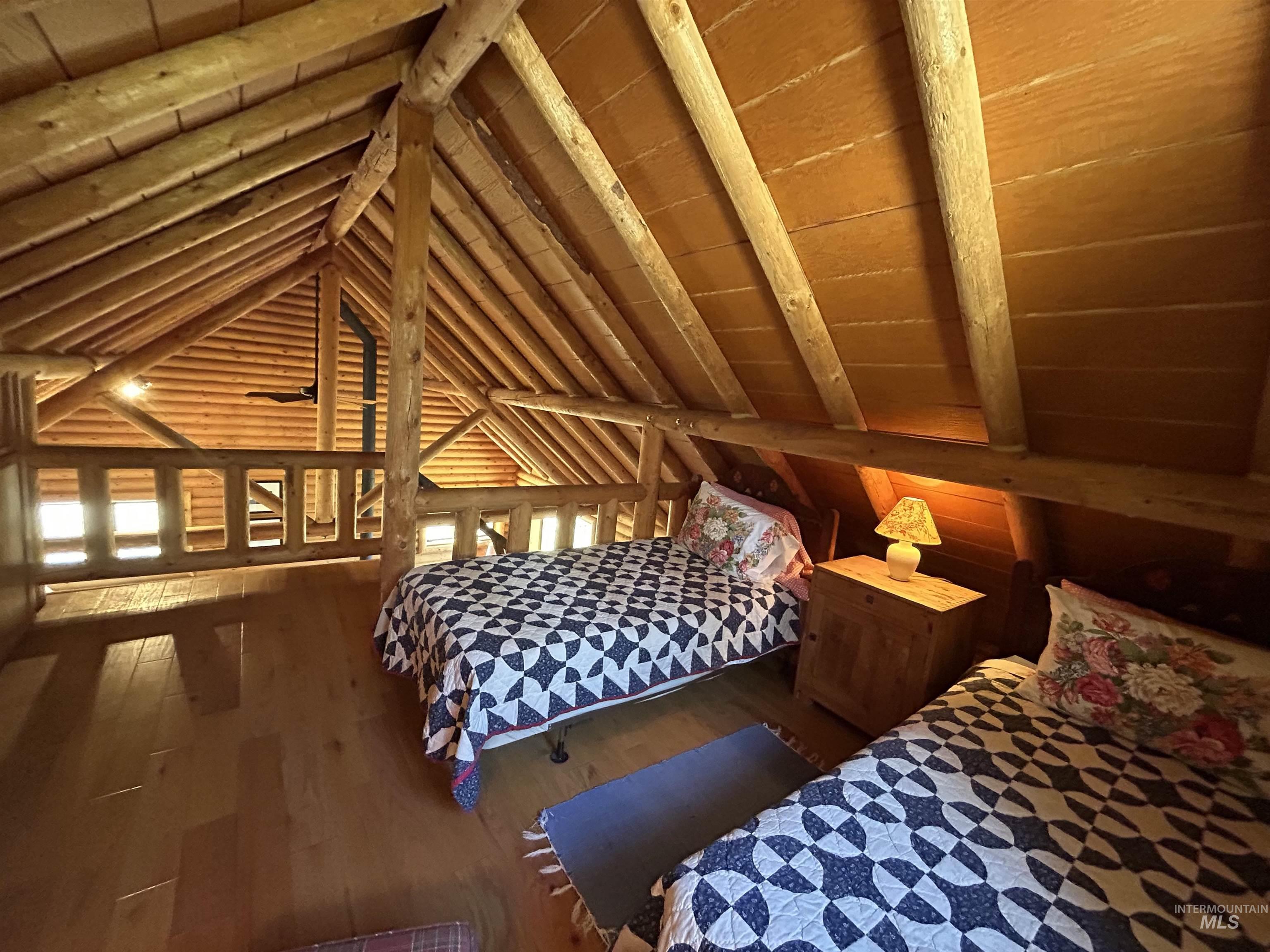 35 Sawtooth Way Stanley, ID 83278 - Photo 27 of 36 Loft area featuring prominent exposed wooden beams, wood-finish flooring, and a log-style railing