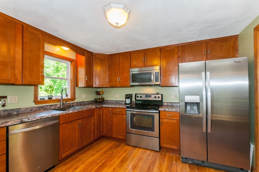 65 Curran Road North Attleboro, MA 02760 - Photo 6 of 19 a kitchen with stainless steel appliances granite countertop a refrigerator a sink dishwasher a stove and white countertops with wooden floor