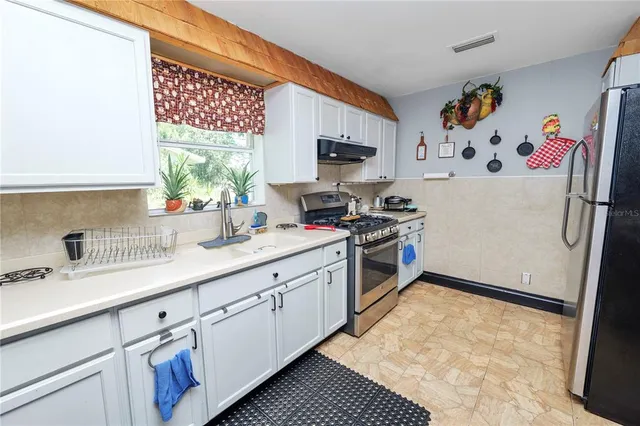 a kitchen with stainless steel appliances granite countertop a refrigerator a stove and a sink with cabinets