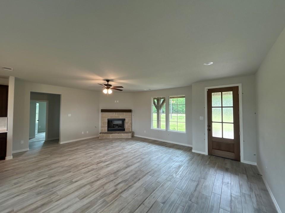 8779 County Road 623 Blue Ridge, TX 75424 - Photo 4 of 12 an empty room with fireplace chandelier fan and windows