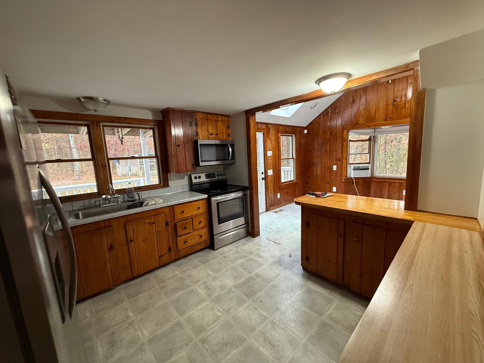 86 Lowell Road Mashpee, MA 02649 - Photo 11 of 18 a large kitchen with stainless steel appliances a large counter top a stove a chimney a sink and a large window