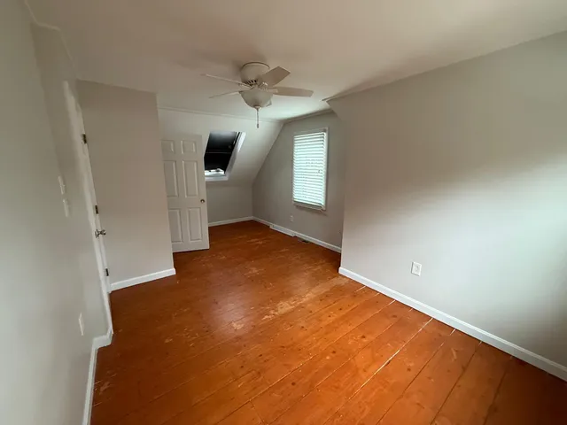 an empty room with windows and chandelier fan
