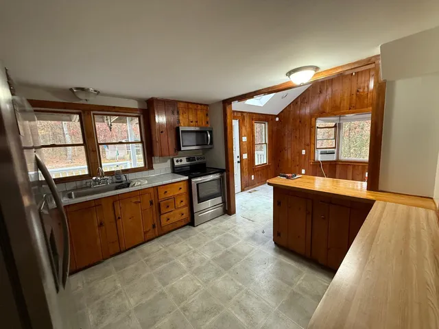 a large kitchen with stainless steel appliances a large counter top a stove a chimney a sink and a large window