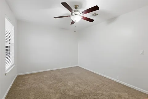 an empty room with window and ceiling fan
