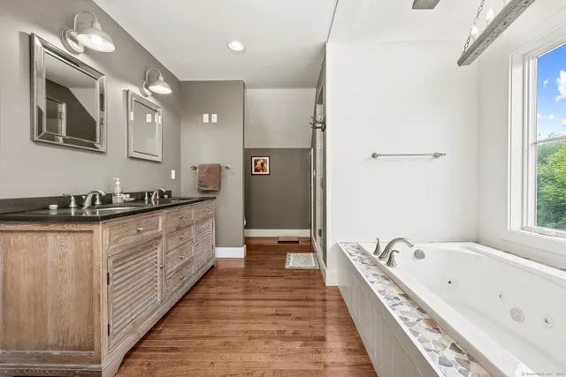a large bathroom with a tub double vanity sink and a large mirror