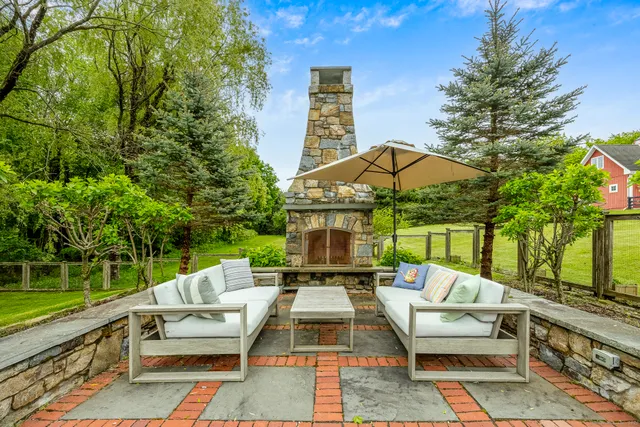 a view of a patio with couches table and chairs under an umbrella