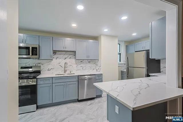 a kitchen with a sink stainless steel appliances and white cabinets