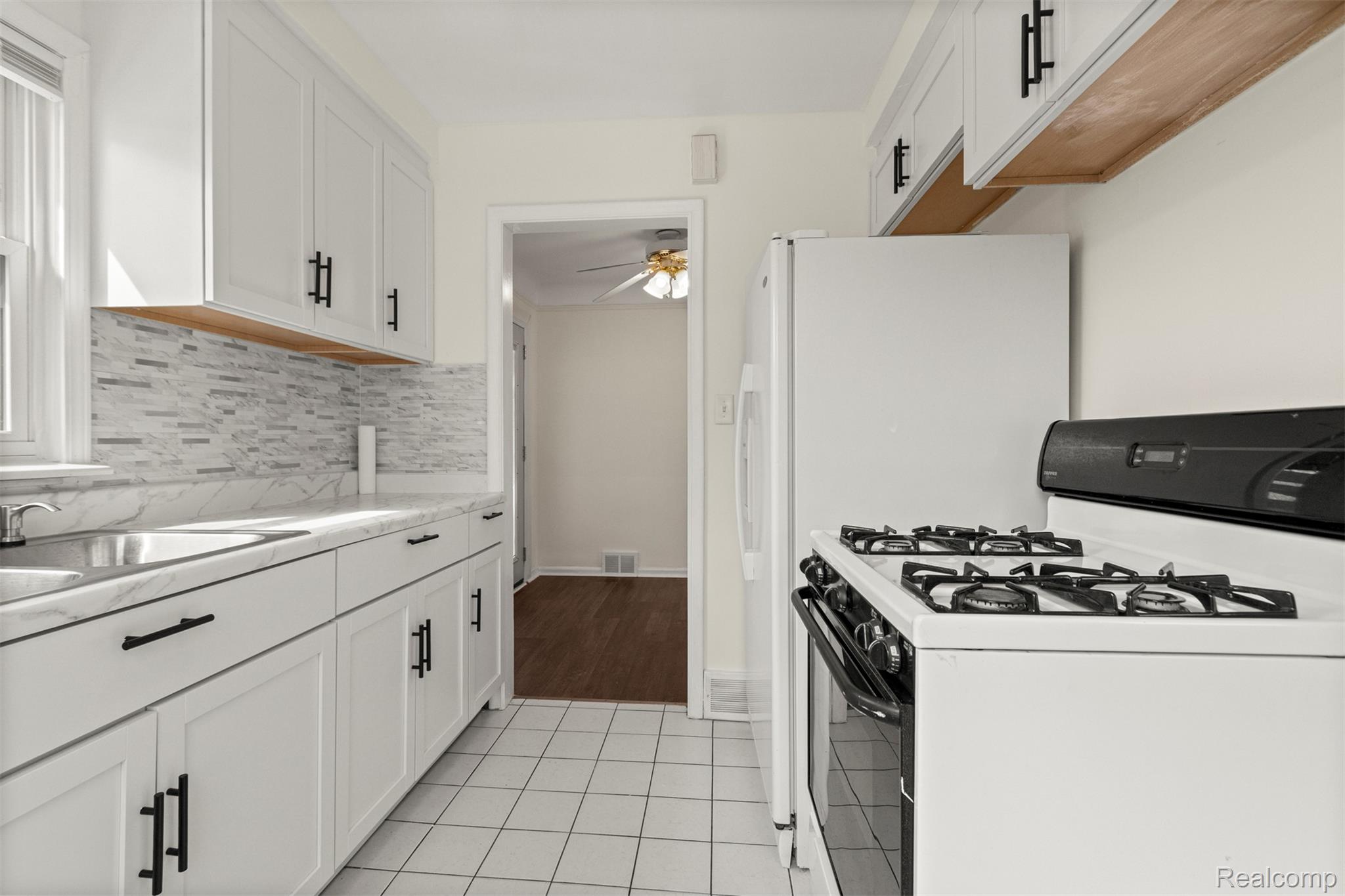 15705 Champaign Road Allen Park, MI 48101 - Photo 10 of 42 Kitchen featuring white gas range oven, white cabinets, light tile patterned flooring, tasteful backsplash, and ceiling fan