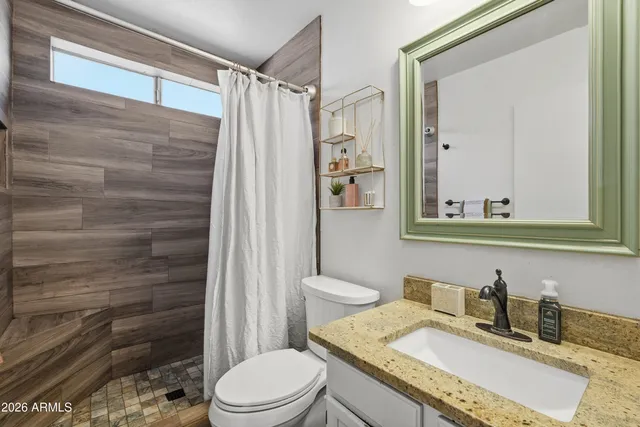 a bathroom with a granite countertop sink toilet and shower