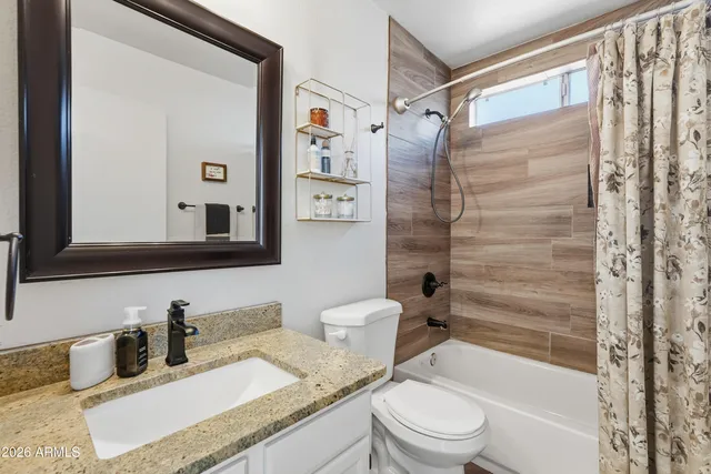 a bathroom with a granite countertop sink toilet a mirror a vanity and shower