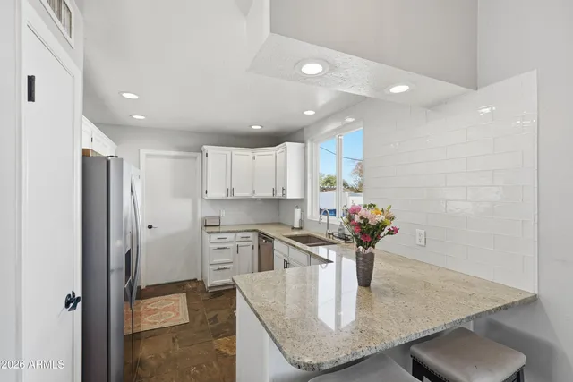 a kitchen with stainless steel appliances granite countertop a sink refrigerator and cabinets