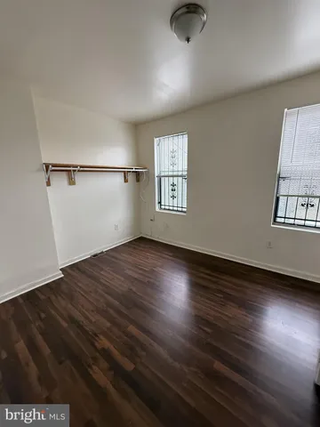 an empty room with wooden floor cabinet and windows