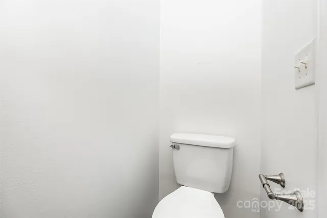 a white toilet sitting next to a white wall