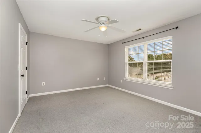 an empty room with window and ceiling fan