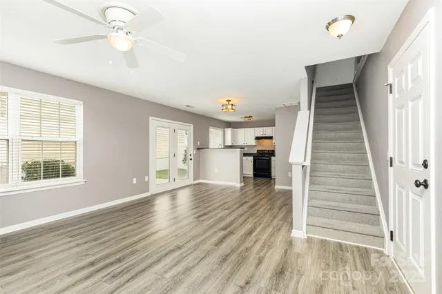 wooden floor in an empty room with a kitchen and a window