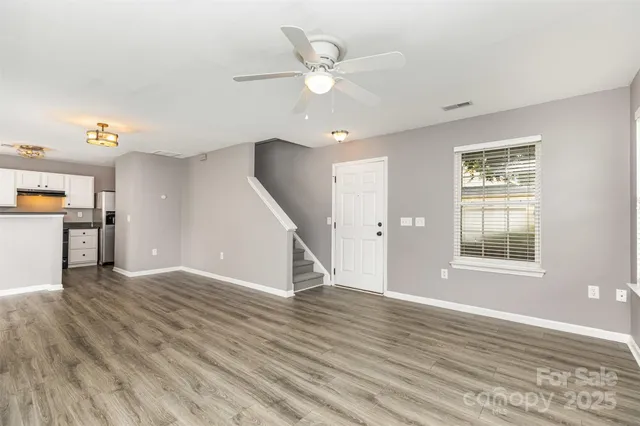 an empty room with wooden floor and ceiling fan