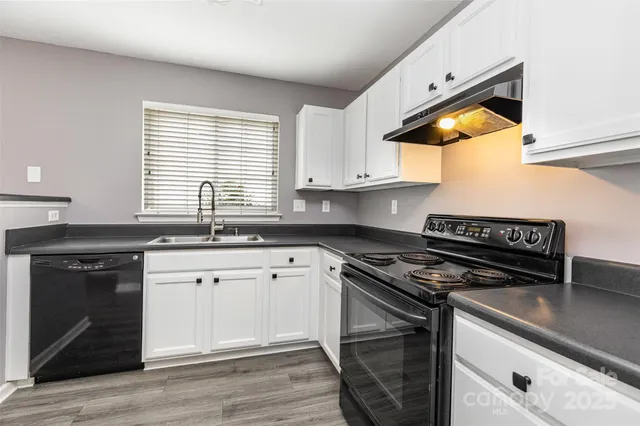 a kitchen with granite countertop a stove a sink and wooden floor
