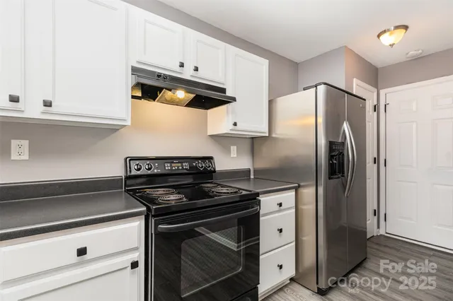 a kitchen with stainless steel appliances granite countertop a refrigerator a stove and white cabinets