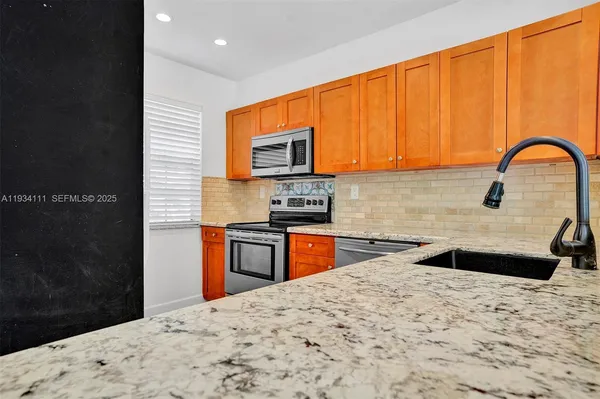 a kitchen with granite countertop a refrigerator and a stove top oven