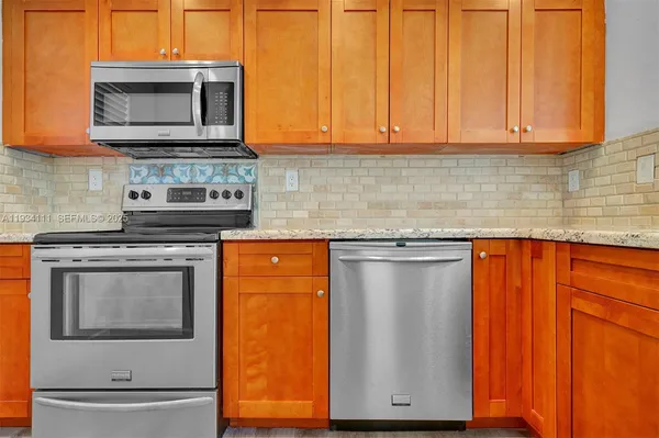 a kitchen with granite countertop wood cabinets stainless steel appliances and a sink