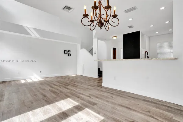 a view of a hallway with wooden floor and chandelier