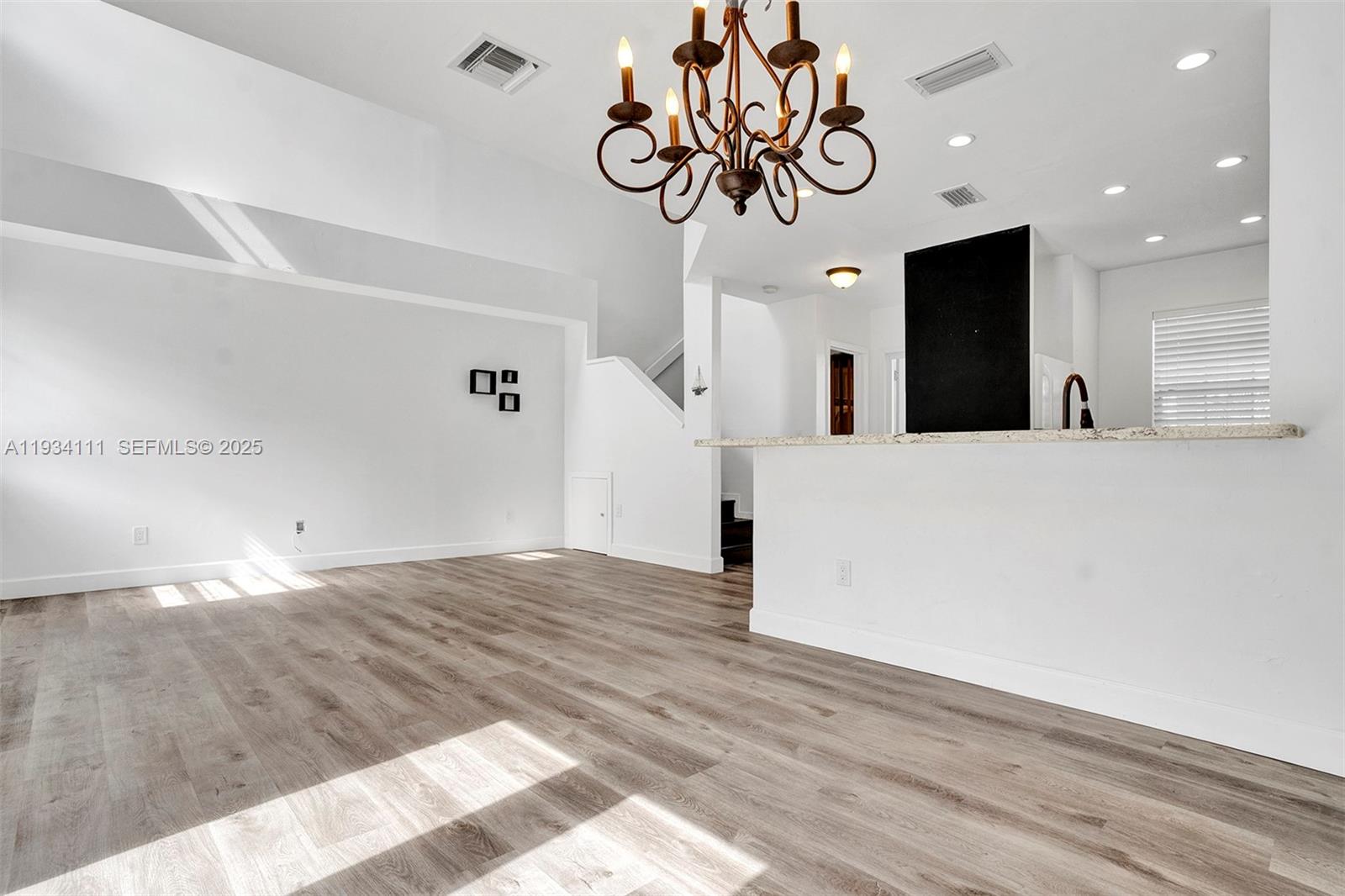 20985 Southwest 84th Avenue Cutler Bay, FL 33189 - Photo 21 of 36 a view of a hallway with wooden floor and chandelier