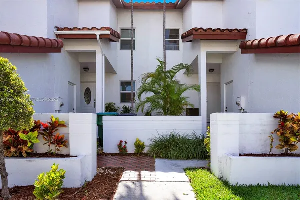a front view of a house with a yard and potted plants