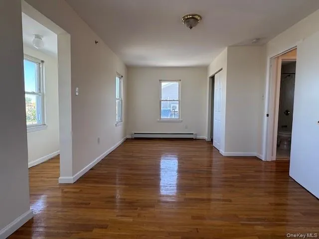 a view of empty room with window and wooden floor