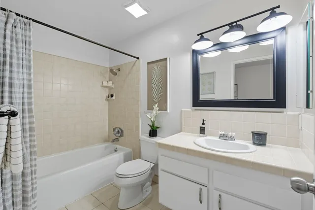 a bathroom with a toilet a sink a mirror a bathtub and shower