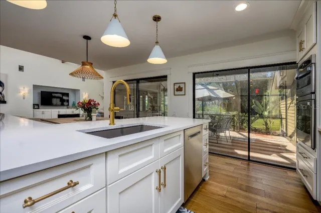 a kitchen with stainless steel appliances granite countertop a sink a counter space and a view of living room