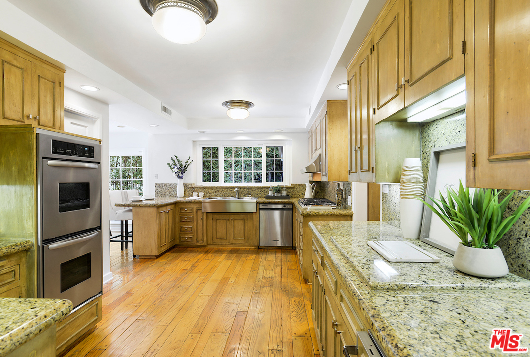 1124 Laurel Way Beverly Hills, CA 90210 - Photo 11 of 31 a kitchen with stainless steel appliances granite countertop a refrigerator a stove top oven a sink dishwasher and dining table with wooden floor
