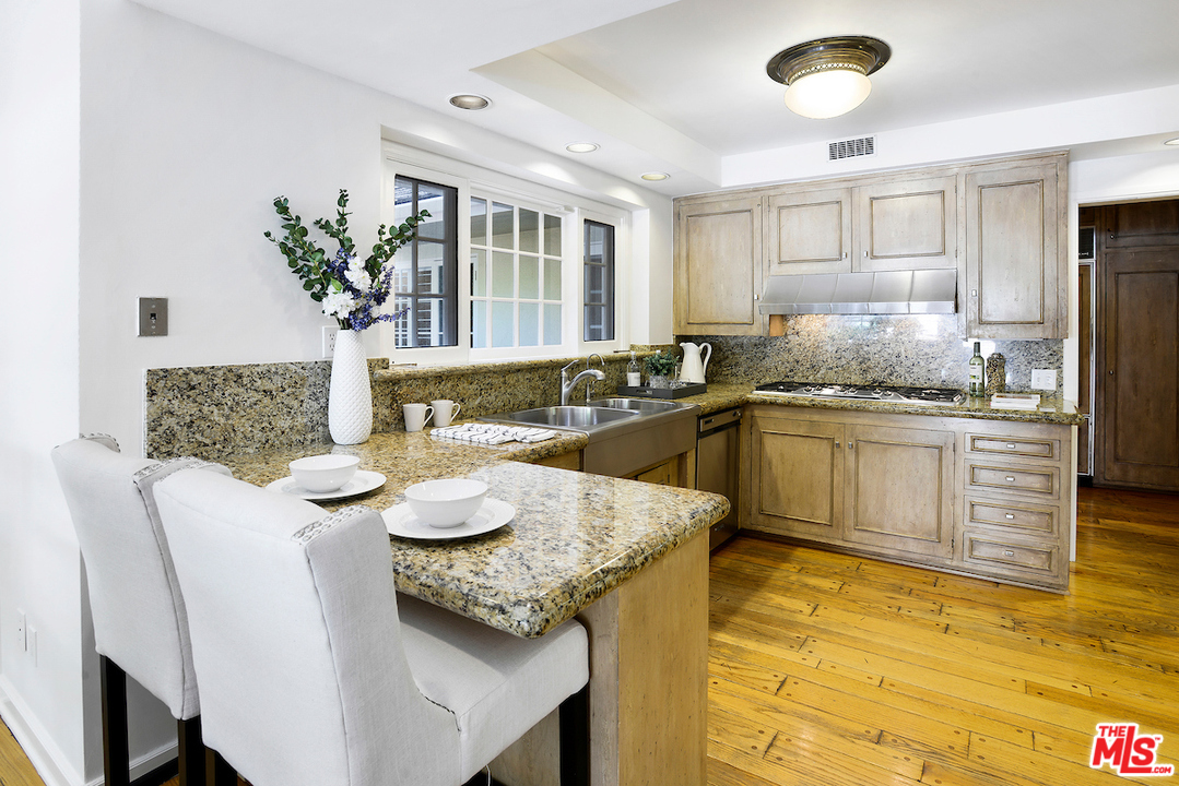 1124 Laurel Way Beverly Hills, CA 90210 - Photo 12 of 31 a kitchen with granite countertop a sink and white cabinets