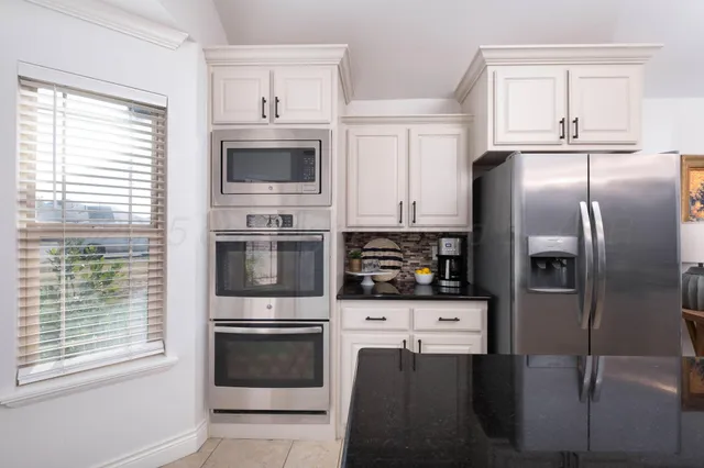 a kitchen with stainless steel appliances a refrigerator a stove a microwave and a window