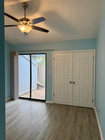 an empty room with wooden floor chandelier fan and windows