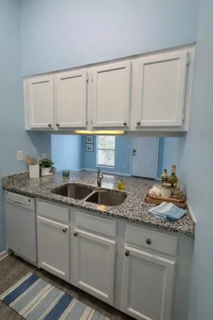 a kitchen with granite countertop white cabinets and a sink