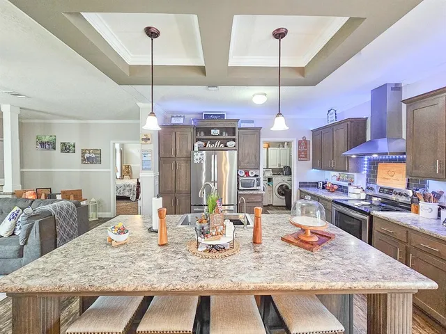 a kitchen with kitchen island a stove a counter top space a sink and living room view