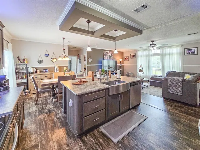 a living room with stainless steel appliances kitchen island granite countertop a table chairs and a wooden floor
