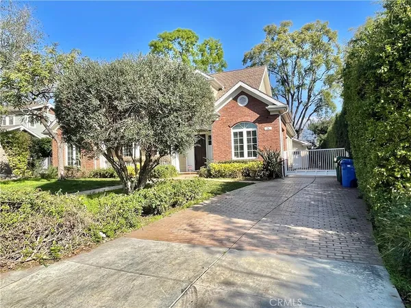 a front view of a house with a garden and trees